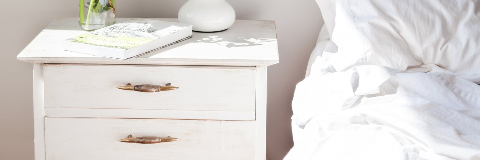 white bedside table next to a bed